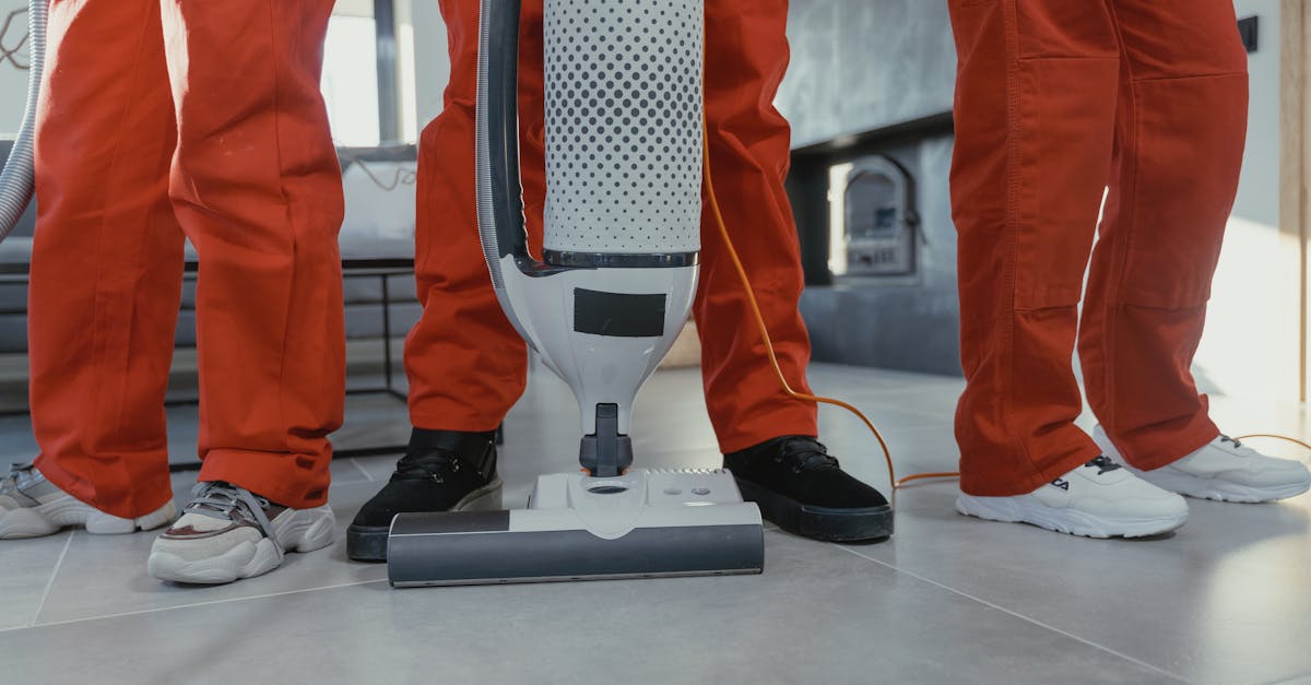 Team of professional cleaners in red uniforms using a vacuum cleaner indoors.